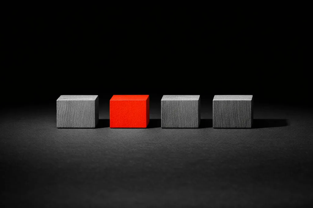 Four small wooden blocks arranged in a horizontal row on black surface, second block from left in matte vermillion, representing one qualifying rail among the e-wallet options